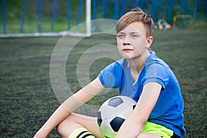 Boy footballer sitting on field