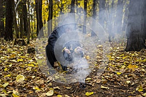 A boy in the forest is lighting a fire. Concept: lost in the forest, survival in the wild, lost without parents, a young traveler,