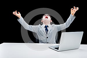 Boy in formal suit and eyeglasses working with laptop and screamed