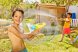 Boy with friend shoot water pistols on summer day