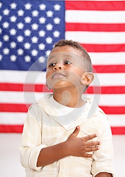 Boy in front of American flag with hand over heart photo