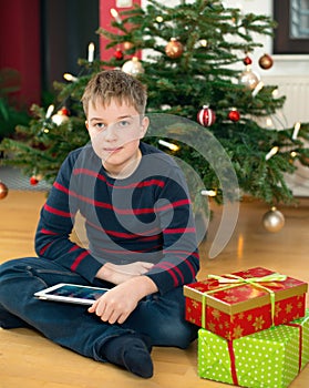 Boy in front of christmas tree with his new tablet pc