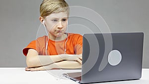 A boy in front of a computer on online distance learning folded his hands in front of him and listens attentively to the teacher