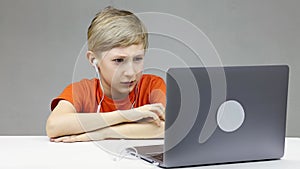 A boy in front of a computer on online distance learning folded his hands in front of him and listens attentively to the teacher