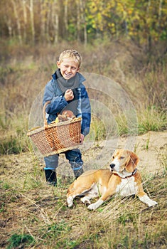 Boy with full basket of mashrooms on the forest glade