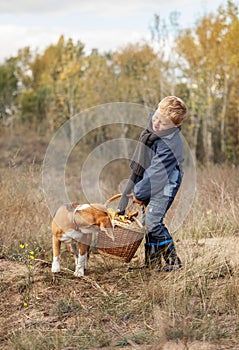 Boy with full heavy basket of mushrooms on the forest glade