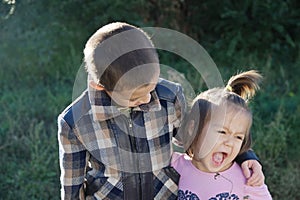 Boy and funny little girl hugging portrait. Happy smiling children outdoors at sunny day. Friendship siblings