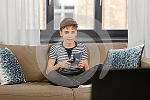 Boy with gamepad playing video game at home