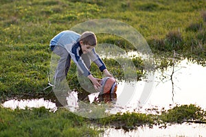 Boy gets ball with puddles in the grass photo