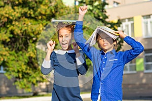 A boy and a girl with books on their heads are happy about the new academic year.