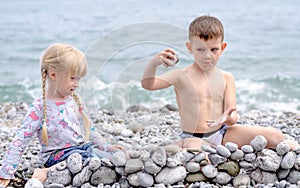 Boy and Girl Building Stone Wall on Rocky Beach