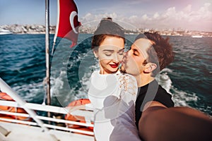 Boy and girl, couple. Make selfie on board a boat cruise vacation. Against the backdrop of the Turkish flag, the sea and