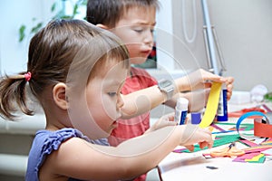Boy and girl cutting paper for craft, brother and sister playing