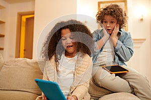 A boy and a girl with devices watching something online