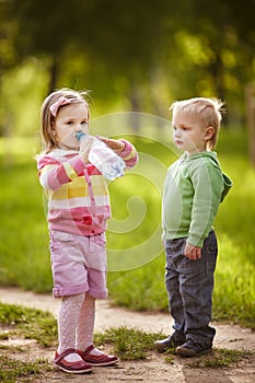 Boy and girl drinking mineral water in park