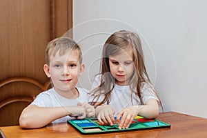 A boy and a girl of European appearance in light clothng sit and play a Board game photo