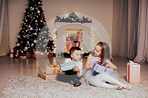 Boy and girl family opens Christmas gift new year holiday lights Christmas tree garlands