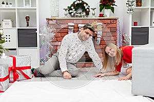 Boy and girl in festive outfits sit by the fireplace