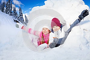 Boy and girl flourish their arms from a snow hole