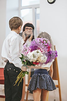 Boy and girl give flowers as a school teacher in teacher`s day