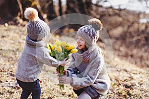 A boy and a girl having fun outside in early spring in the forest near the water. A sister and brothe together.
