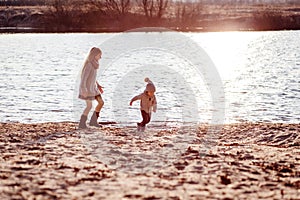 A boy and a girl having fun outside in early spring in the forest near the water. A sister and brothe together.