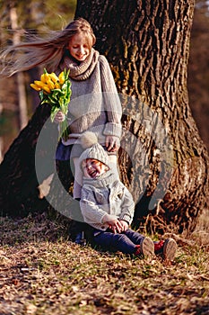 A boy and a girl having fun outside in early spring in the forest near the water. A sister and brothe together.