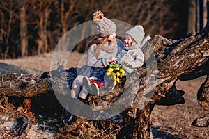 A boy and a girl having fun outside in early spring in the forest near the water. A sister and brothe together.