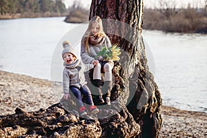 A boy and a girl having fun outside in early spring in the forest near the water. A sister and brothe together.