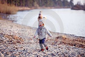 A boy and a girl having fun outside in early spring in the forest near the water. A sister and brothe together.