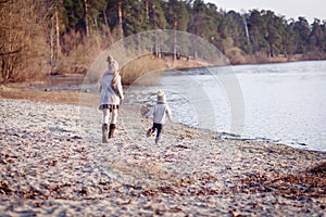 A boy and a girl having fun outside in early spring in the forest near the water. A sister and brothe together.