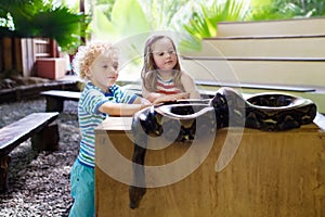 Boy and girl hold and feed python snake at zoo