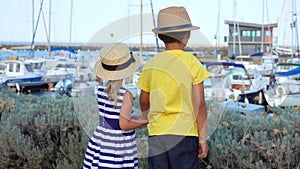Boy and girl hold hands on the quay of yacht port