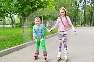 Boy and girl holding hands and roller skating in the Park in sum