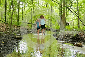 Boy and girl holding hands while walking in a creek