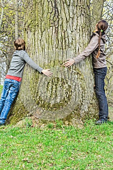 Boy and girl hugging old tree