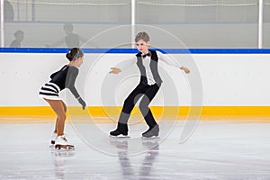 A boy and girl ice skaters are performing a routine on the ice