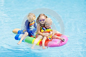 Kids on inflatable float in swimming pool.