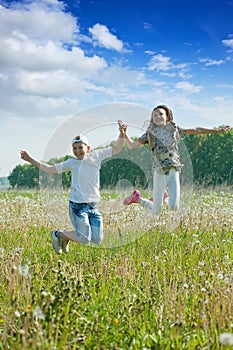 Boy and girl jumping at meadow
