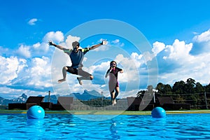Boy and girl jumping into the pool in the lake.