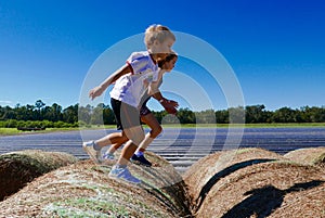 Boy and girl jumping and running on haystacks