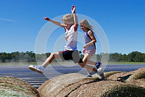 Boy and girl jumping and running on haystacks