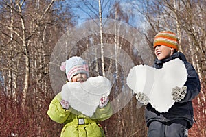 Boy and girl keeps in hands hearts from snow photo