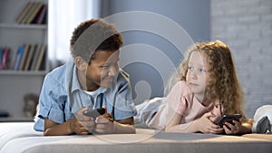 Boy and girl looking each other interest while competing mobile game, friendship