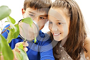Boy and girl looking at a plant through a magnifying glass