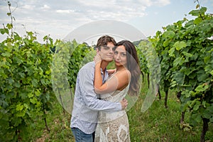 Boy and girl in love look smilingly at the photographer who portrays them in the midst of the vineyards photo