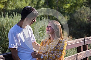 boy and girl in love looking at each other and talking, leaning against a wooden fence