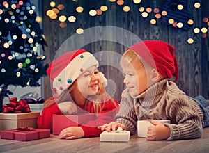 Boy and girl lying on the floor with presents near christmas tree