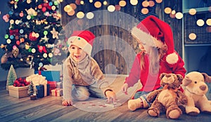 Boy and girl lying on the floor with presents near christmas tree