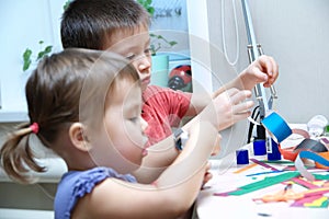 Boy and girl making craft with paper with glue